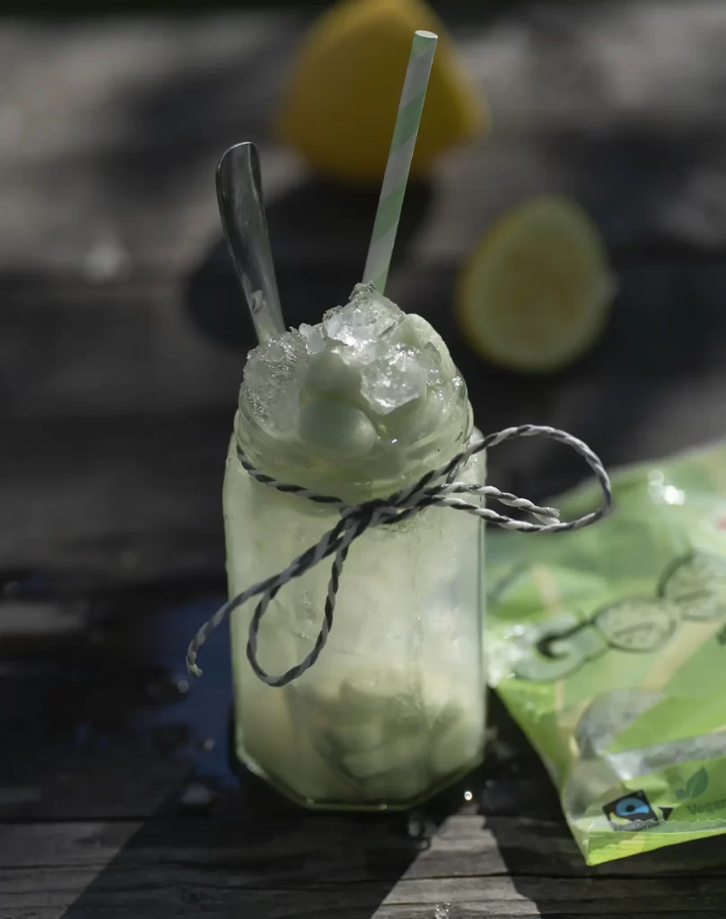 Drink i glasburk med sugrör. Bredvid en godispåse. 