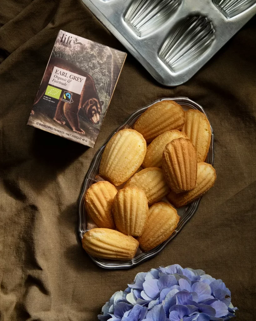 Snäckskalsformade kakor på ett fat. Ett paket Earl Grey-te. 