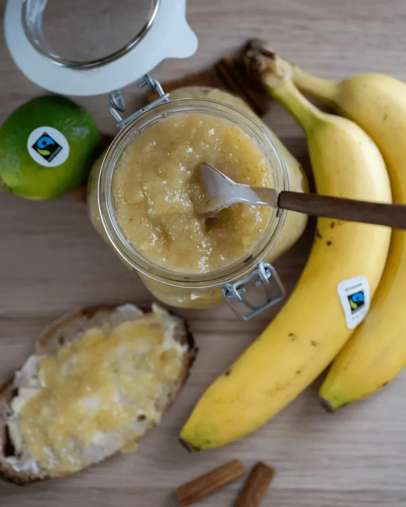 Burk med banansylt omgiven av bananer och lime. 
